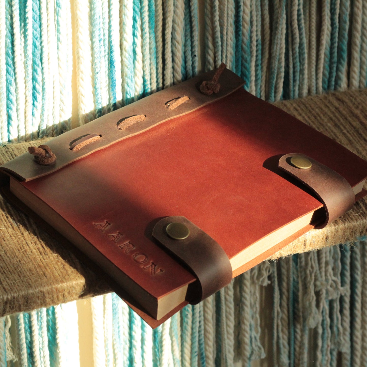 Zamknięty, elegancki dziennik z grawerem inicjałów leżący na stosie książek.