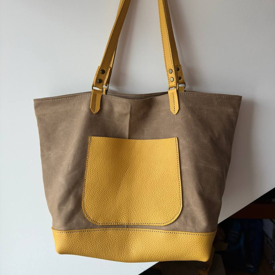 Torba midi w kolorze khaki na tle miejskiej architektury.