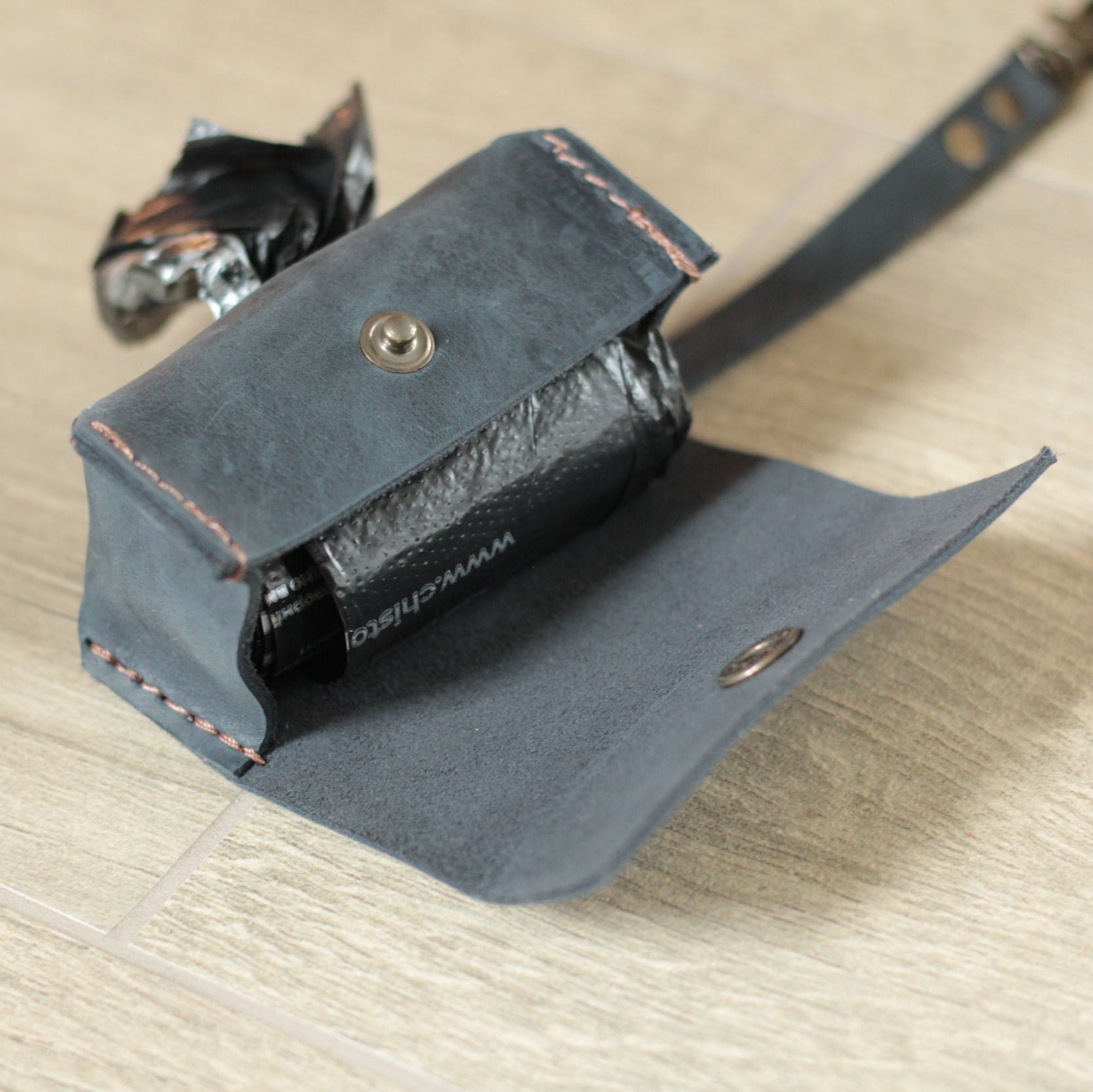 Dispenser przymocowany do obroży psa za pomocą praktycznej zawieszki.

