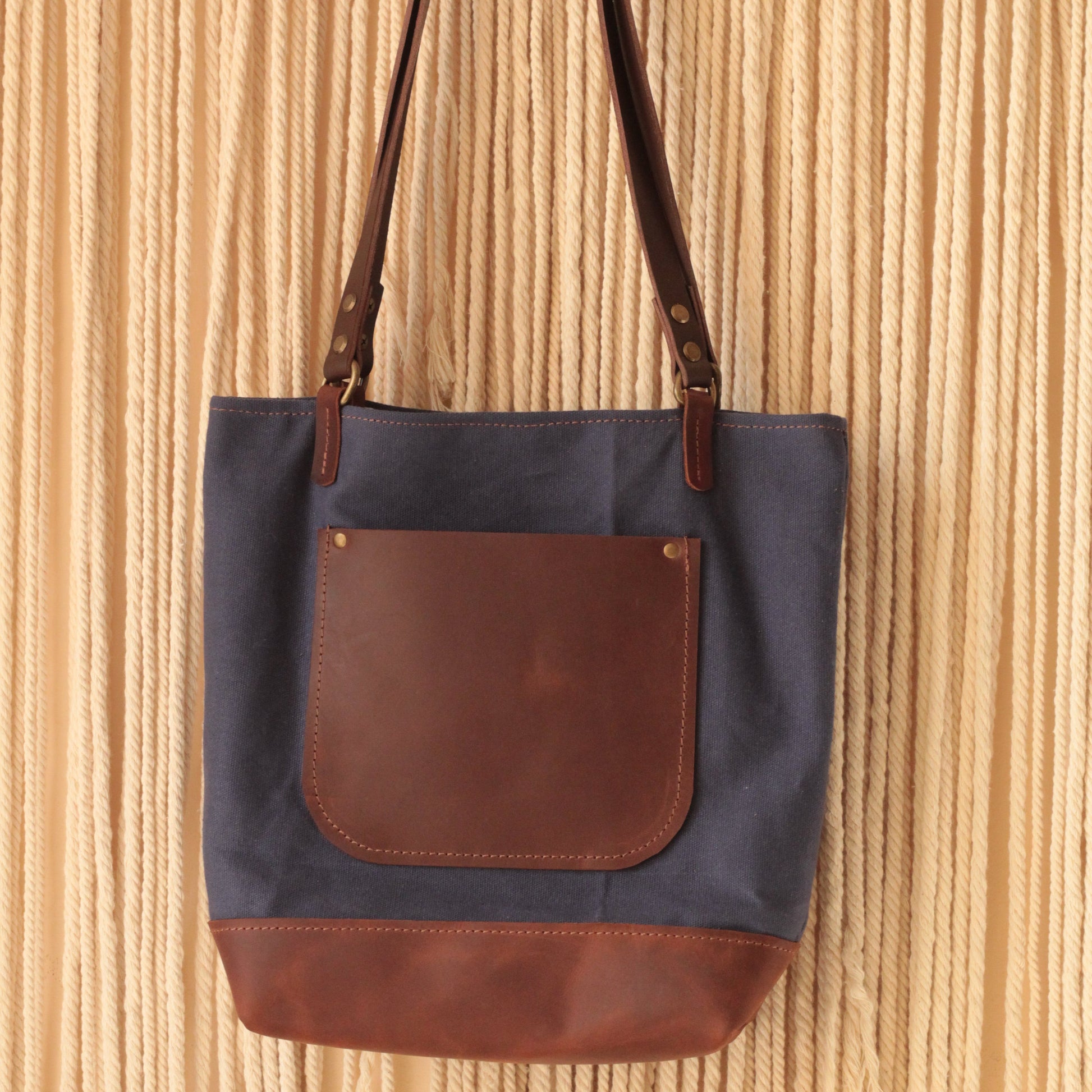  torba z woskowanego płótna ze skórzanym dnem i brązowymi uchwytami.

