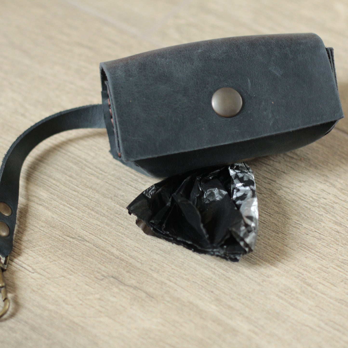 Brązowy skórzany dispenser na tle parkowej ławki i zieleni