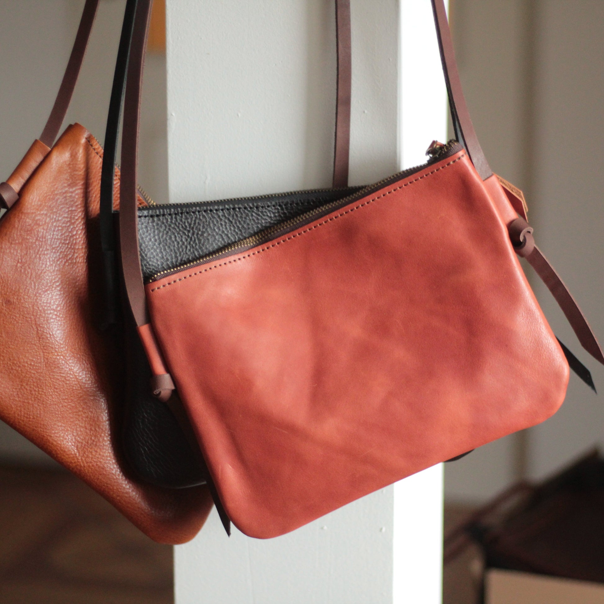 Torba postawiona na półce obok butów i akcesoriów w neutralnych kolorach.

