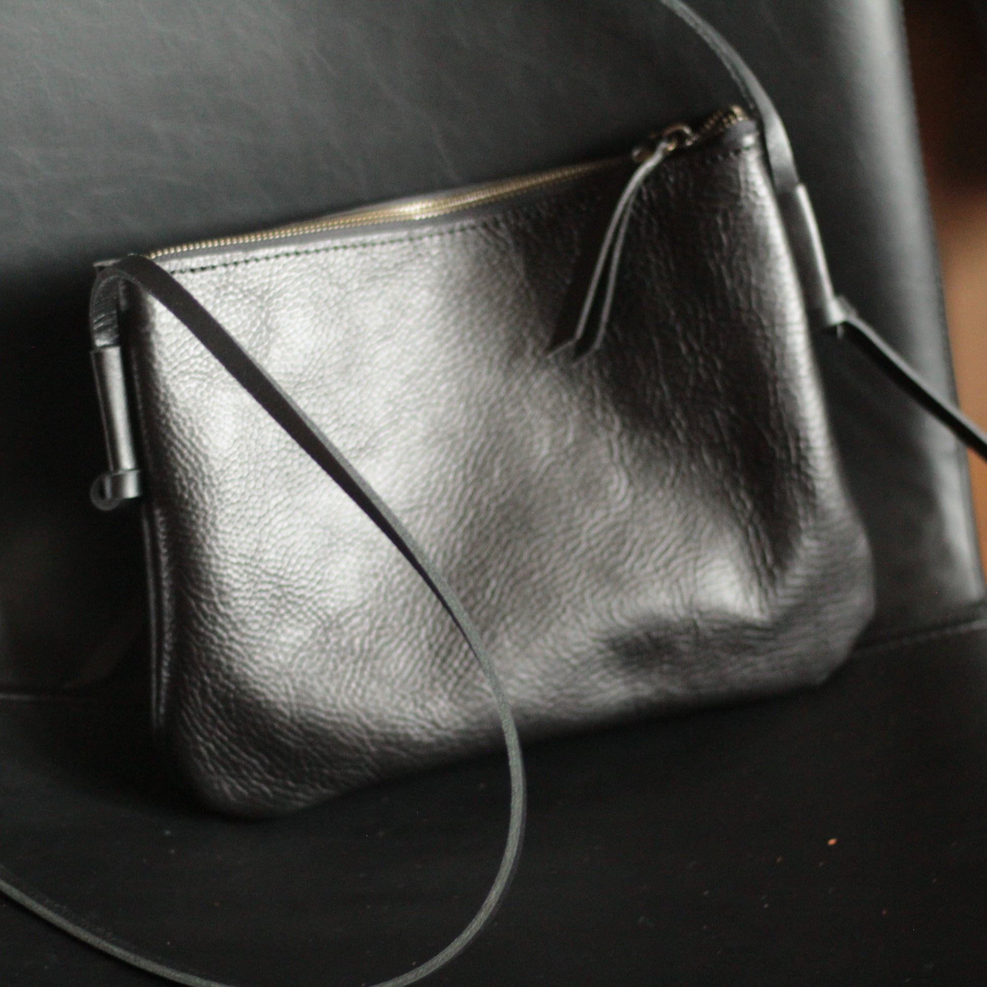 Kobieta nosząca skórzaną torbę krosobdi na ramieniu w miejskiej scenerii.

