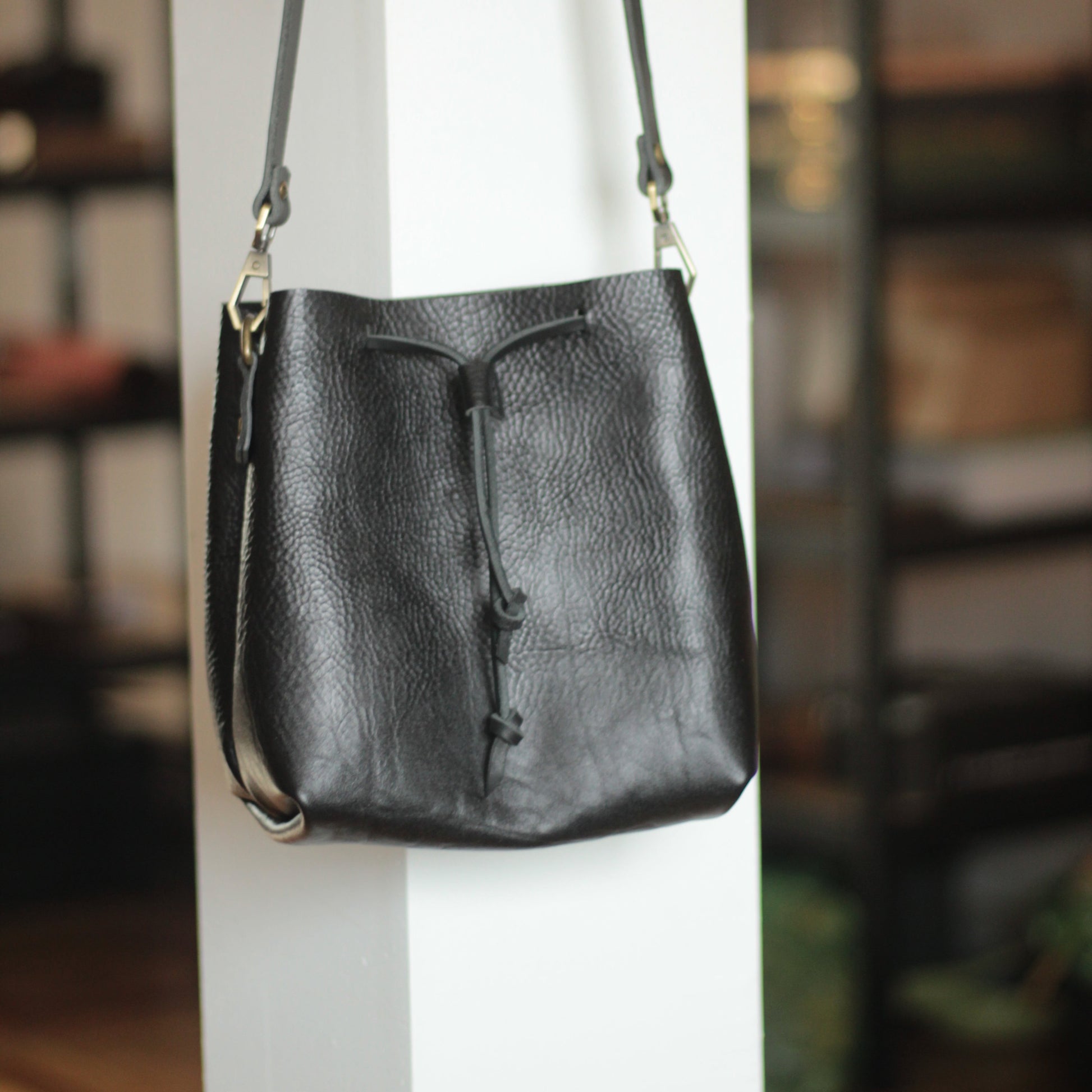 Torba bucket wypełniona codziennymi niezbędnikami: portfelem, książką, butelką wody.

