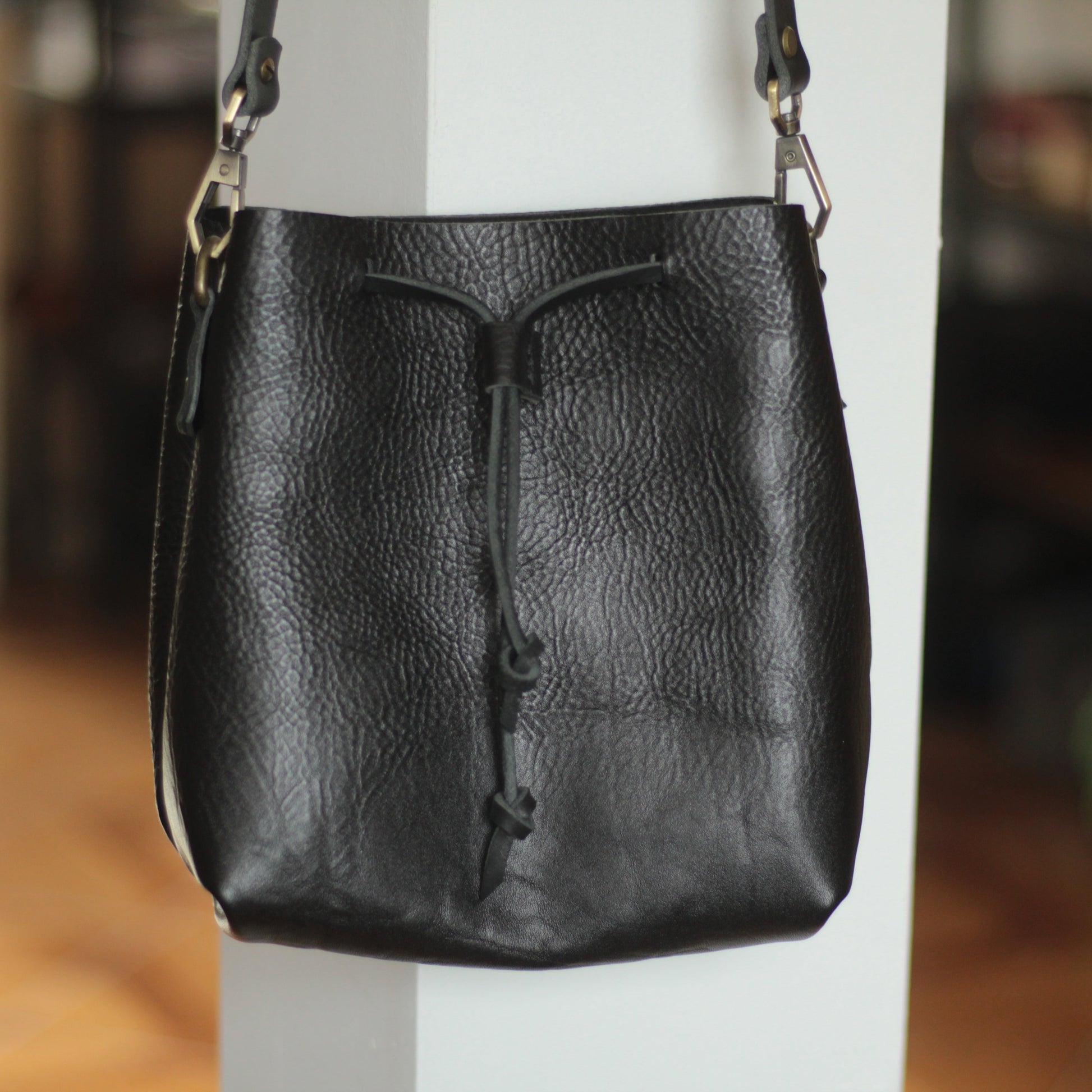 Zbliżenie na mechanizm zamykania torby na sznurek i skórzaną klapkę.

