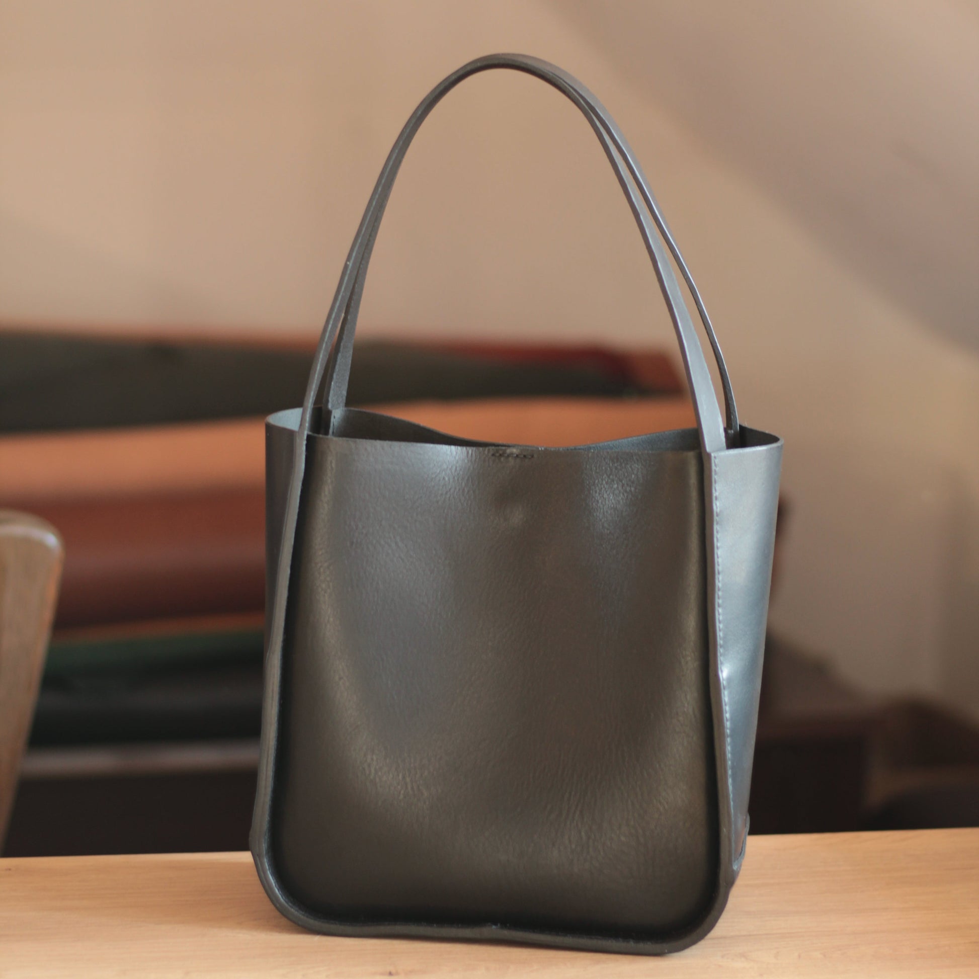 Pusta torba tote stojąca, ukazująca swoją kwadratową, ale miękką sylwetkę.

