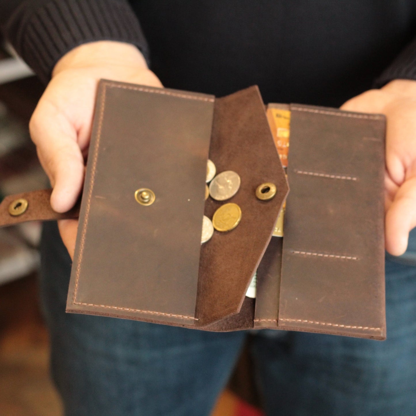 Portfel obok iPhone'a, demonstrujący, że telefon mieści się w głównej przegródce.

