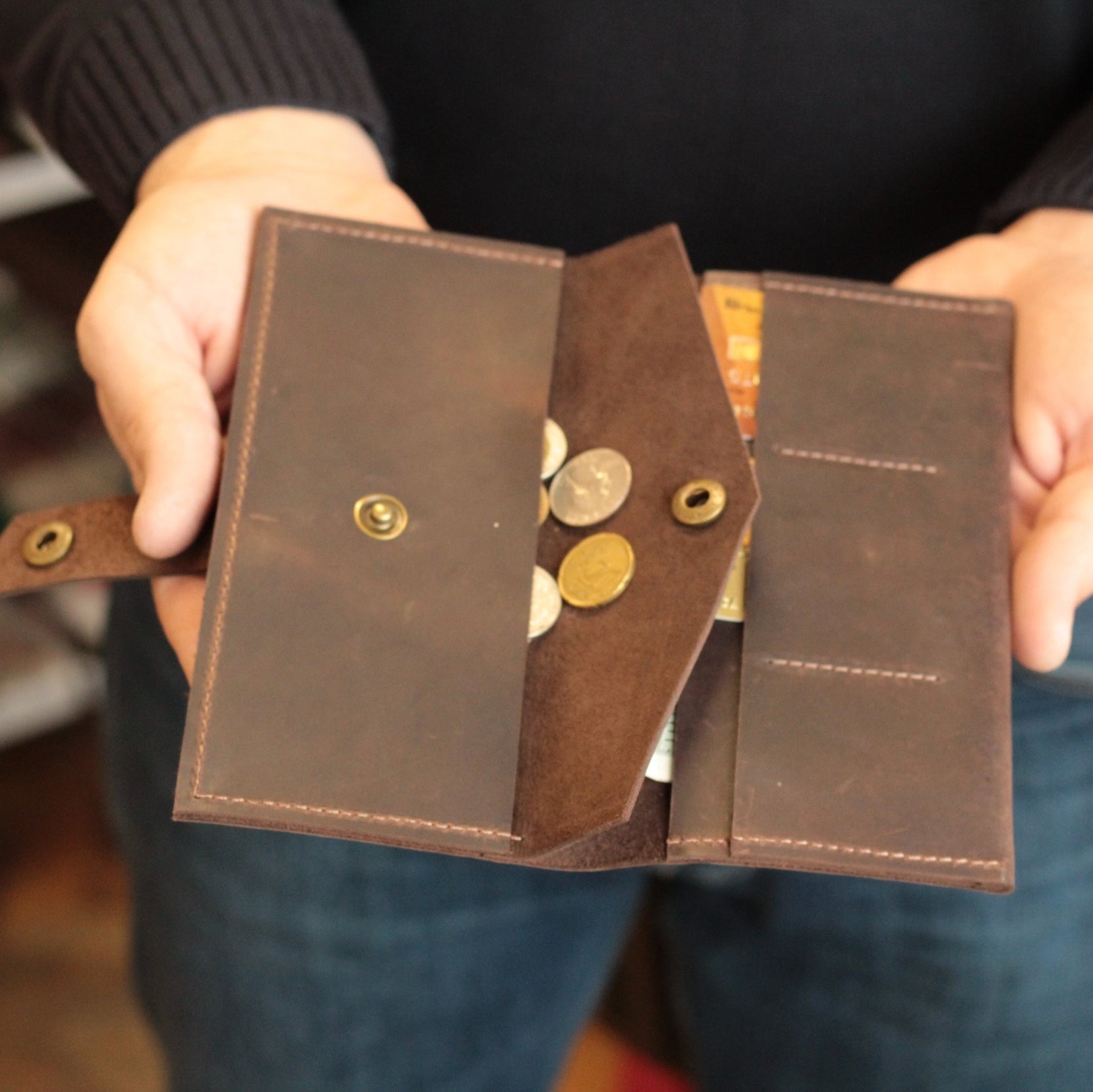 Portfel obok iPhone'a, demonstrujący, że telefon mieści się w głównej przegródce.

