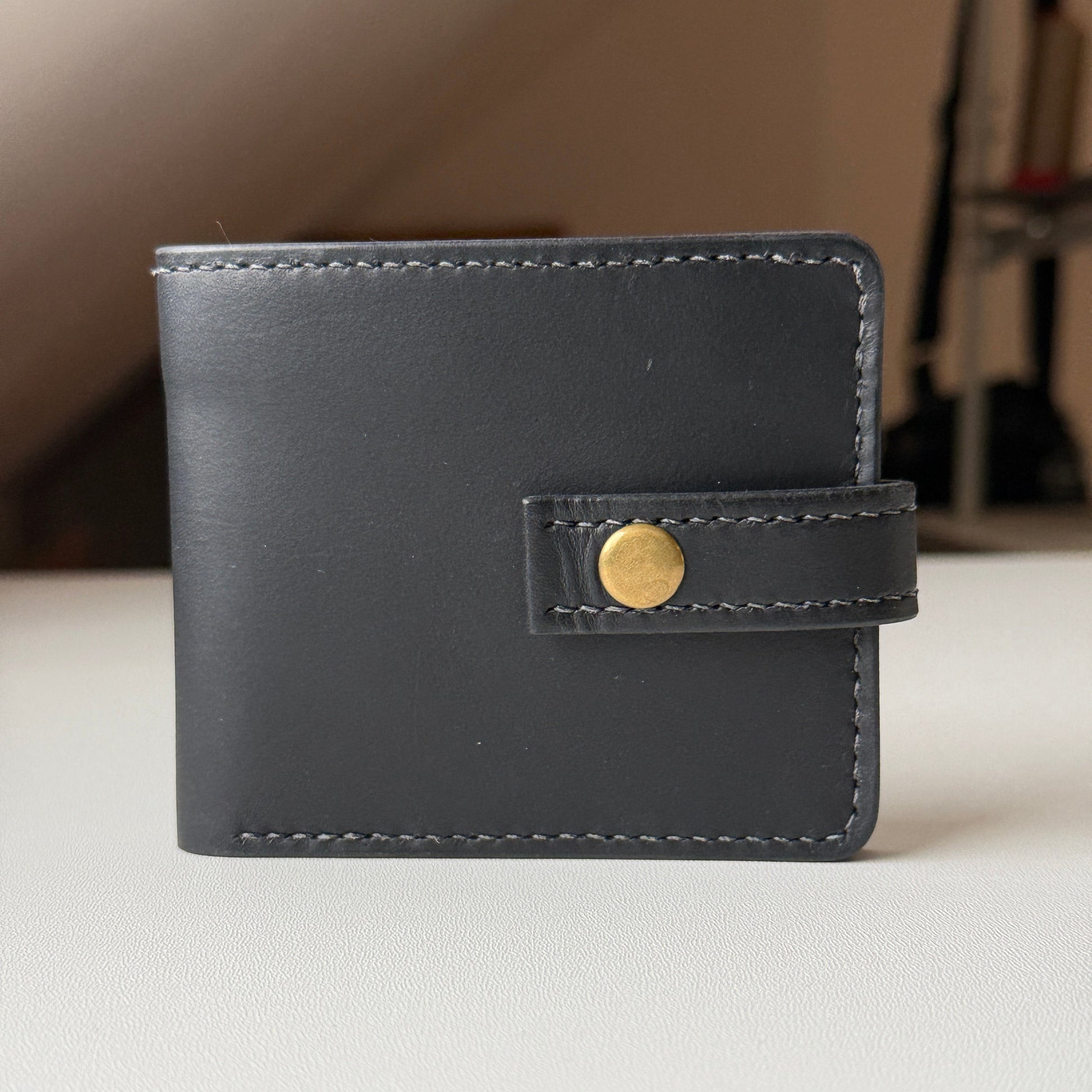 Klasyczny brązowy skórzany portfel bifold, zamknięty, z widoczną fakturą skóry licowej.

