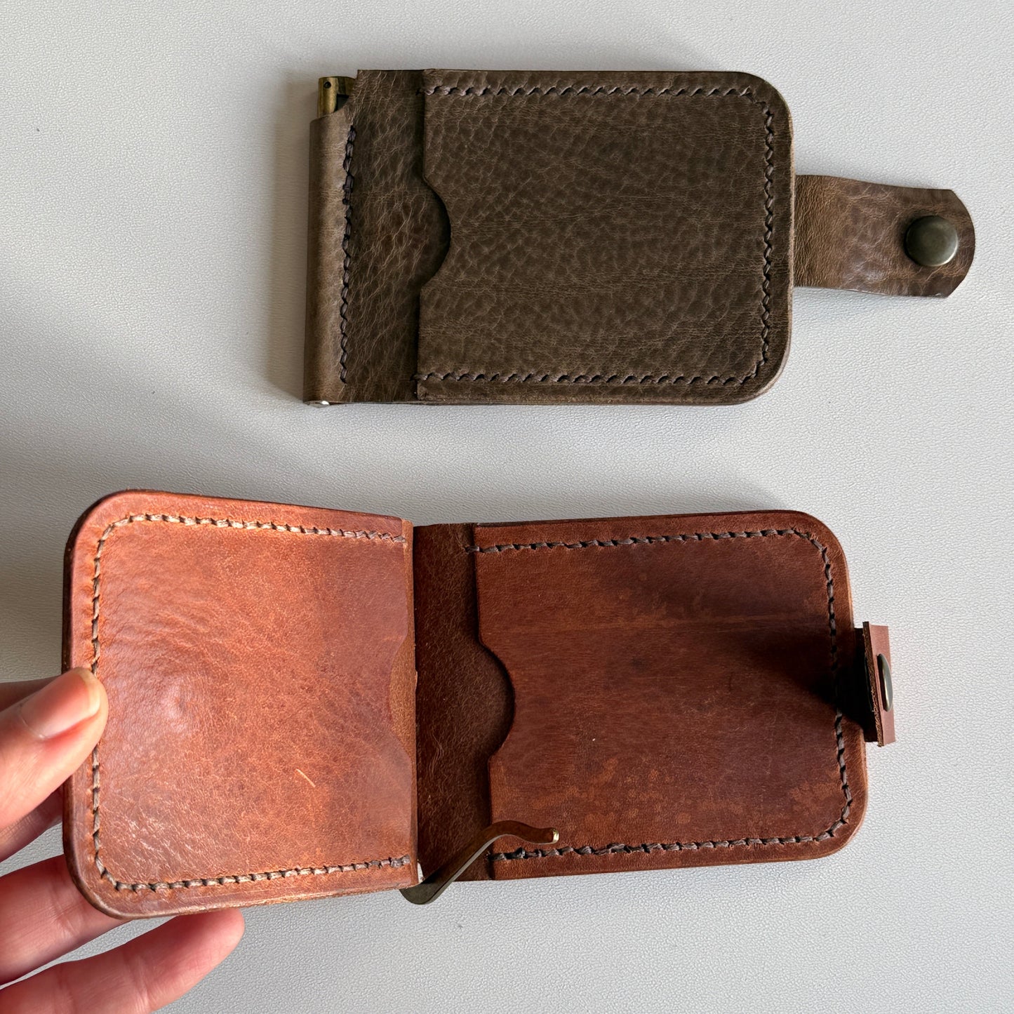 Ręcznie robiony portfel ze skóry licowej, otwarty, z widocznymi kartami i banknotami.


