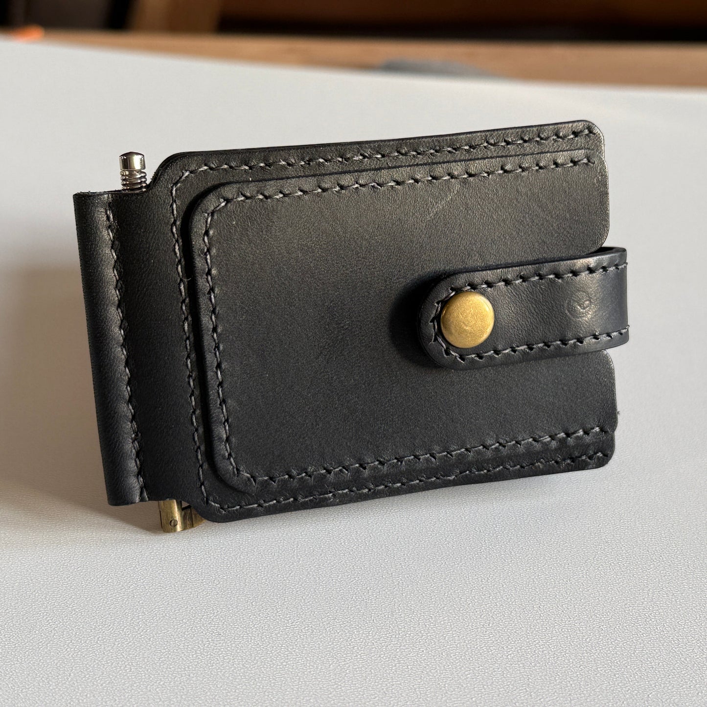 Ręcznie wykonany minimalistyczny portfel z klipsem magnetycznym otwarty, pokazujący przegrody na karty.

