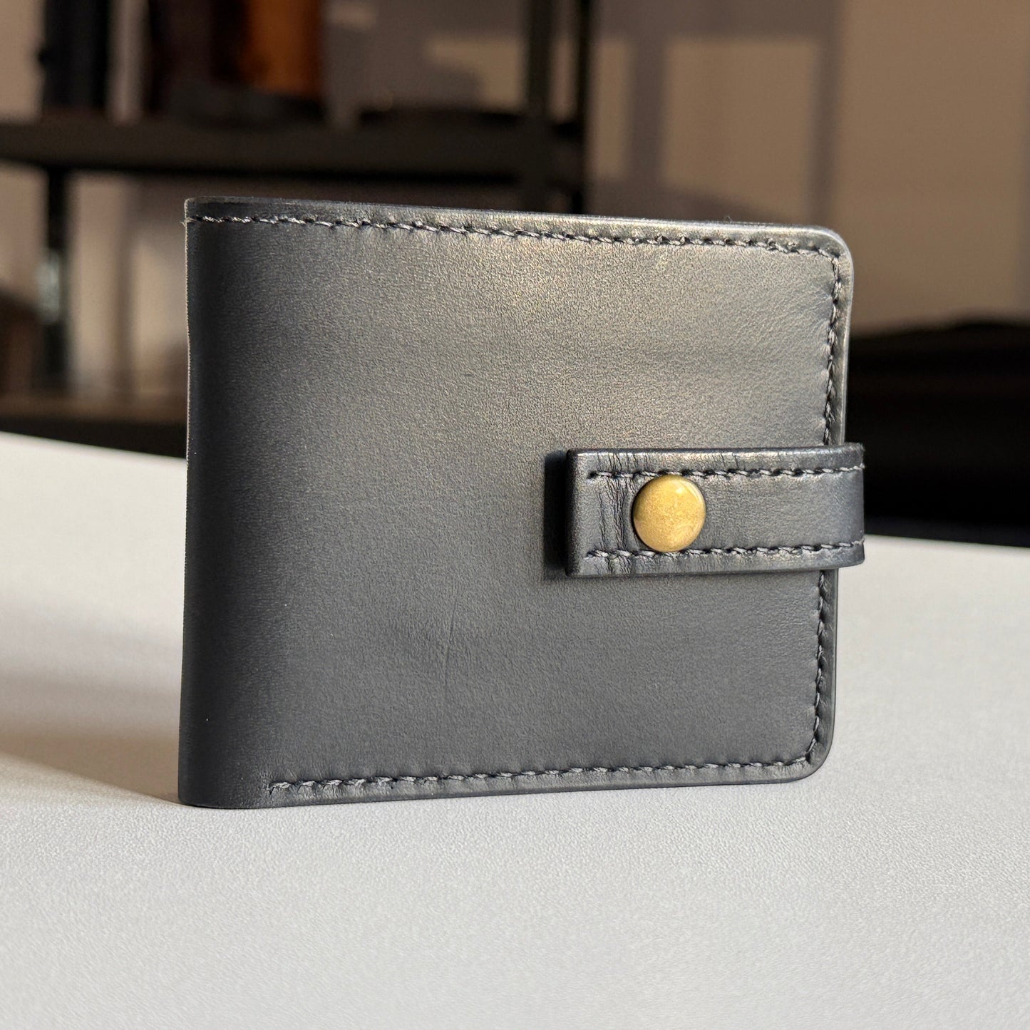 Proces ręcznego szycia portfela – widok na narzędzia i nić.

