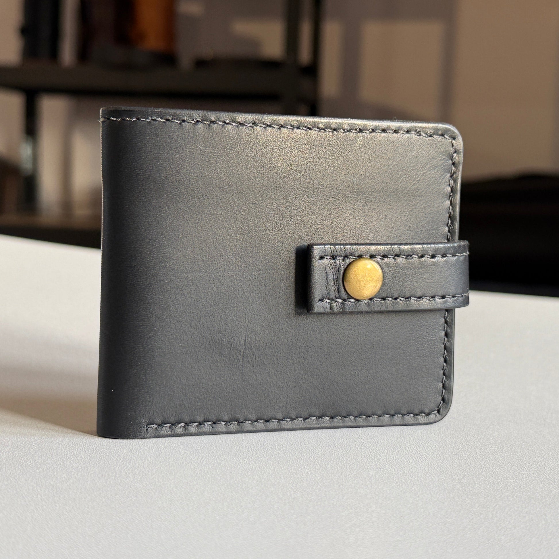 Proces ręcznego szycia portfela – widok na narzędzia i nić.

