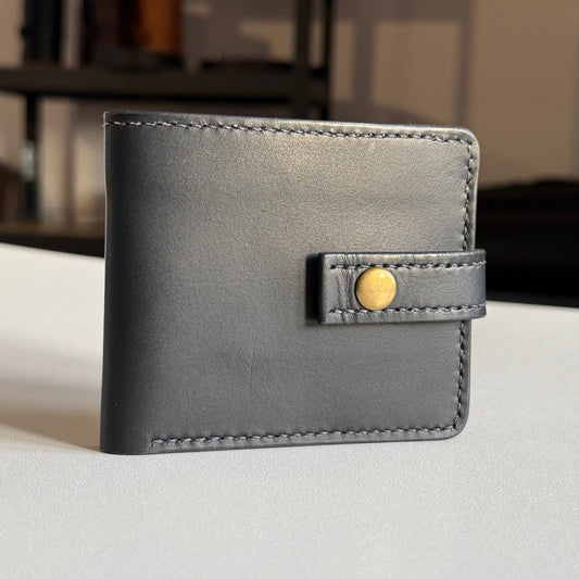 Proces ręcznego szycia portfela – widok na narzędzia i nić.

