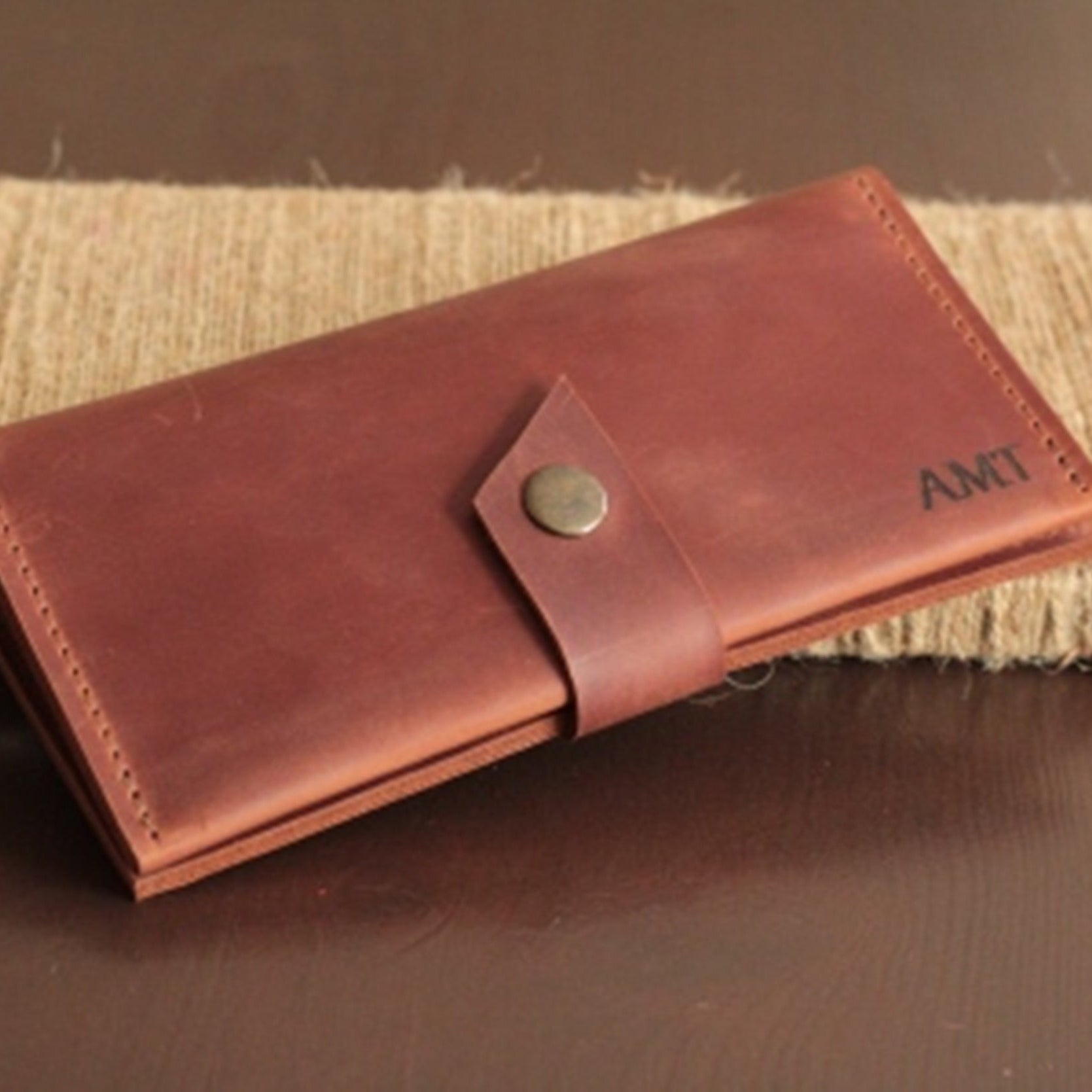 Dłoń trzymająca zamknięty, kompaktowy portfel damski (wymiary 19x10 cm).

