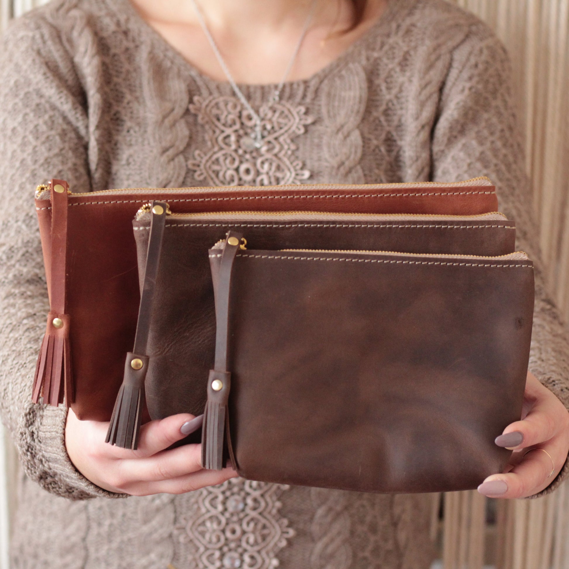 Różne kolory skórzanych toreb na kosmetyki: czarny, brązowy i szary.

