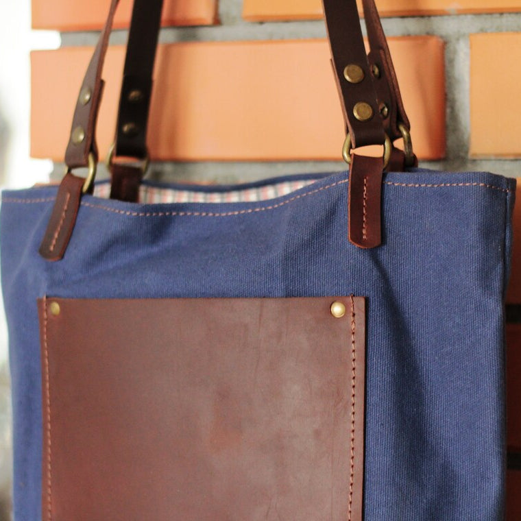 Torba waxed canvas rzucona na kamienie lub trawę – w naturalnym otoczeniu.

