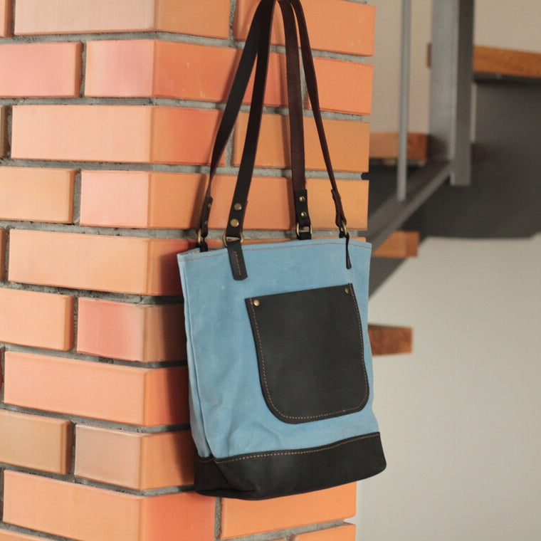 Torba stojąca na skórzanym dnie, ukazująca swój stabilny, trapezowy kształt.

