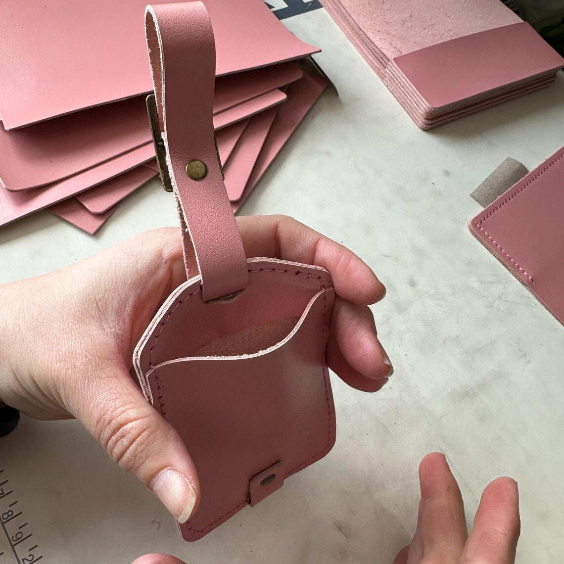 Zawieszka z grawerem logo firmy przymocowana do teczki biznesowej.

