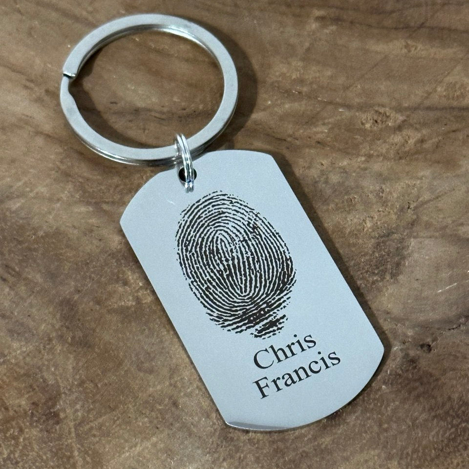 Spersonalizowany brelok ze stali nierdzewnej z grawerowanym odciskiem palca i napisem na klucze - elegancka pamiątka.

