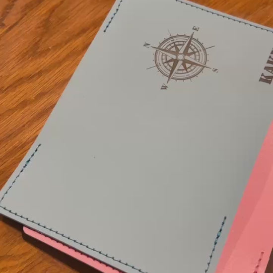 Elegancka, czarna okładka na paszport leżąca obok biletu lotniczego i okularów przeciwsłonecznych.

