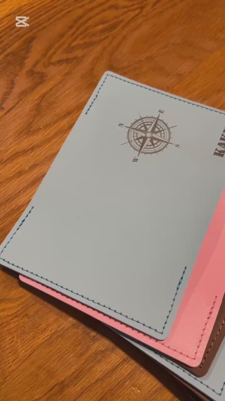 Elegancka, czarna okładka na paszport leżąca obok biletu lotniczego i okularów przeciwsłonecznych.

