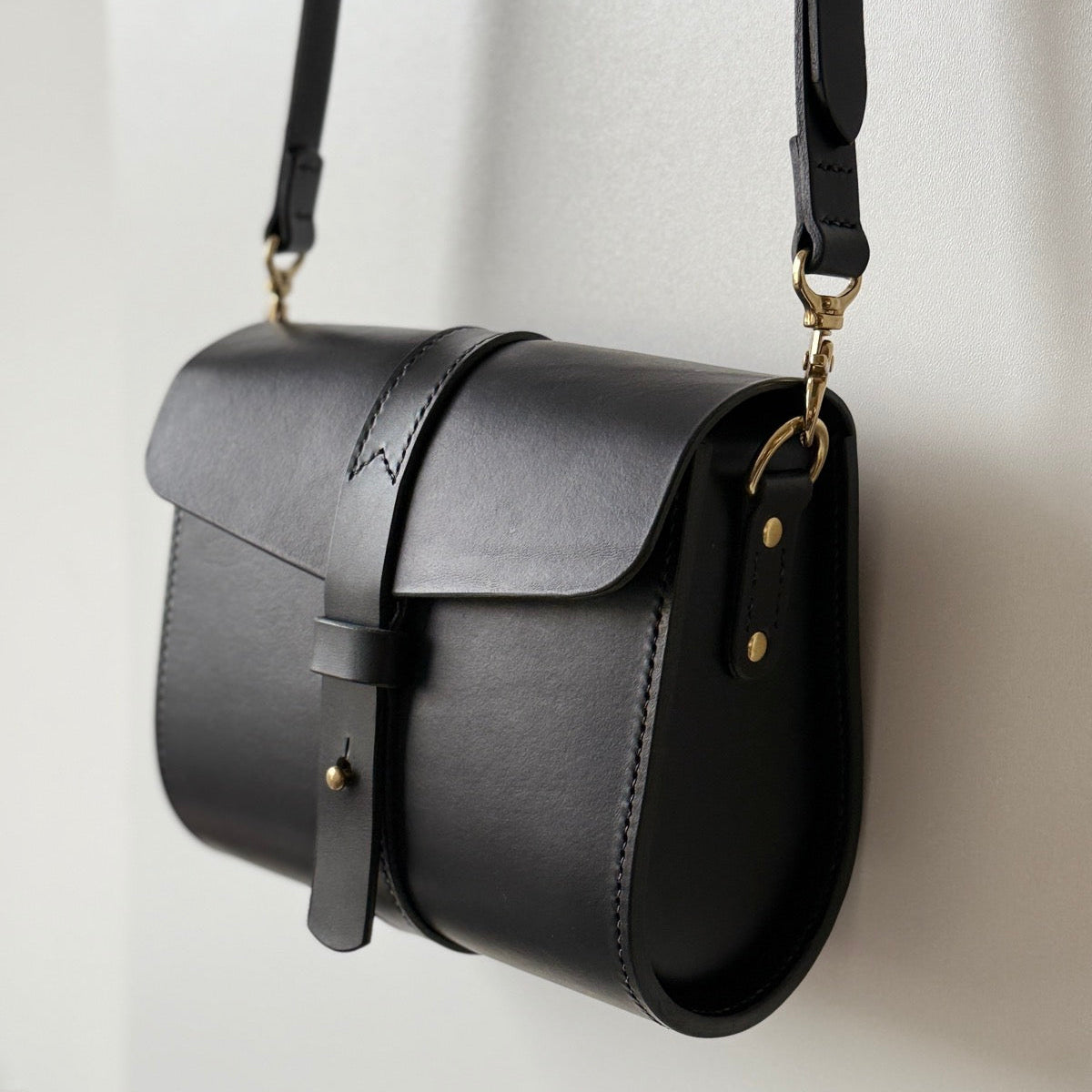 Ręcznie robiona torba na tle warsztatu rzemieślniczego z narzędziami.

